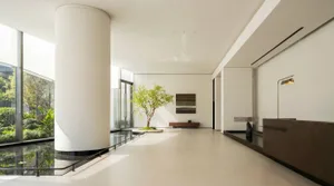 Bright and airy lobby with white walls, floor, and ceiling, featuring natural light and a potted plant