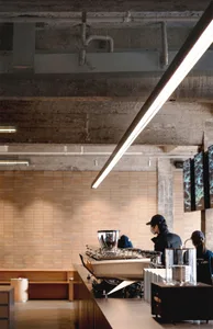 Cozy restaurant interior with a modern bar, brick walls, and a concrete floor, featuring a TV, chair, and dining table