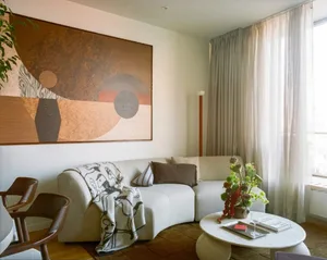 A well-lit living room with a white color scheme, a couch, a chair, and a painting on the wall