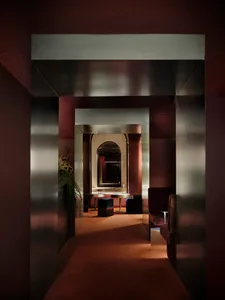 Warm and inviting hallway with red walls, a couch, chair, bench, and a potted plant