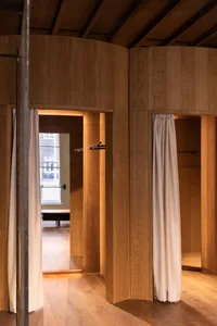 A simple wooden closet with white curtains, wooden walls, and a wooden floor, featuring soft and diffused lighting