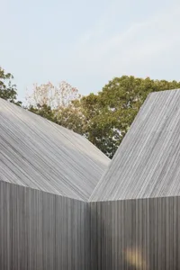 Photograph of a modern building with two sections separated by a wall, featuring wood construction and natural lighting