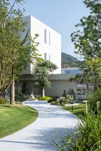 A serene and inviting house with a modern design, surrounded by a lush green lawn and a large tree in front