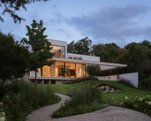 A modern house with a large open living room, dining area, and kitchen, featuring a fireplace, sliding glass door, and natural light