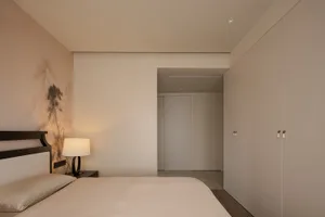 一個具有平靜和邀人的臥室，擁有床、桌子和門，採用中性色彩和簡約裝潢