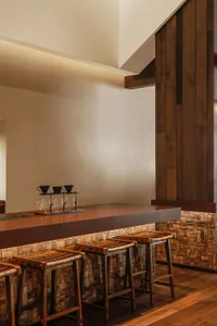 A warm and inviting kitchen with a wooden counter, chairs, and dining table, featuring a coffee maker and cups, set in a cozy atmosphere