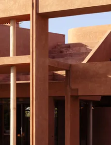 Photograph of a modern building with a red brick exterior, a concrete staircase, and a large window providing natural light