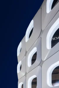 一座白色外牆的現代辦公大樓，透著大玻璃窗，受到自然光的照明