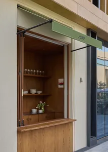 Modern kitchen with a wooden counter, display of plates and bowls, and wine glasses, with a view of the interior through an open door