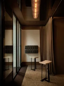Cozy living room with a wooden floor, brown curtain, table, chair, and mirror