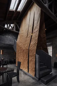 Cozy restaurant dining space with a stone staircase, wooden floor, and dim lighting