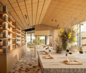 Warm and inviting restaurant with wooden floor, stone counter, and dining tables, adorned with vases and decorative items