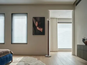 A modern living room with a hardwood floor, rug, and a woman's portrait on the wall, featuring soft and diffused lighting
