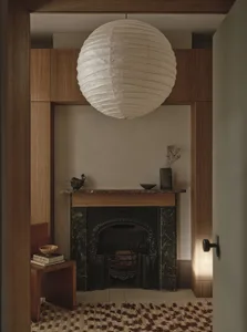 Cozy living room with a stone fireplace, a white lamp, and books scattered around, creating a warm and inviting atmosphere