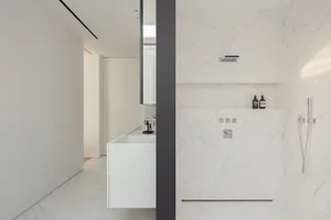 一間現代浴室，具有白色花崗岩桌面、洗手台、鏡子和馬桶，自然光線和簡約設計