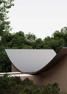 A modern building with a gray roof, metal accents, and a natural atmosphere, surrounded by trees and blending indoor and outdoor spaces