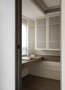 A well-lit kitchen with white cabinets, a wooden countertop, and a book and cup on the counter