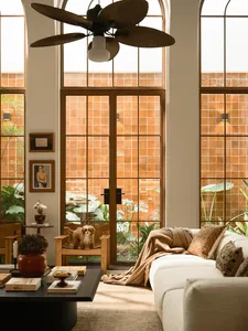 A well-lit living room with a couch, chair, and dog, surrounded by natural light from a large window