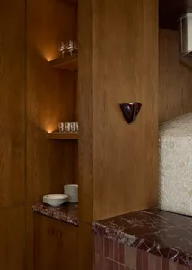 Residential kitchen with wooden cabinets, a marble countertop, and dim lighting creating a cozy atmosphere