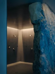 Bathroom with a rock wall, shower, and sink, featuring dim lighting and a moody atmosphere