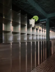 A minimalist storage space with a metal shelf and a green plant, featuring a silver metal shelf and a touch of natural element