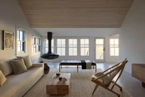 Comfortable living space with a large window, modern furniture, and natural light, decorated with vases, bowls, and a bottle