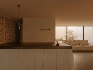 一間現代客廳，擁有大沙發和小桌子，透過大窗戶自然光照明，使用大量白色材料，呈現清潔和明亮的外觀