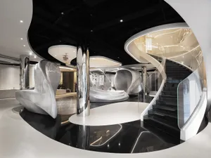 A dimly lit, modern interior space with a spiral metal staircase and a circular room with a black and white color scheme