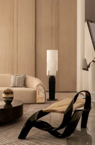 A well-decorated living room with a couch, chair, and lamp, featuring a vase, bowl, and handbag, with a warm and inviting atmosphere