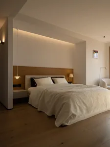 Cozy modern bedroom with a white bed, wooden bench, and wooden floor, well-lit with a warm atmosphere