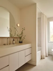 A modern bathroom with a white sink, toilet, and bathtub, set against a white background with a mirror above the sink