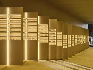 A well-lit store display featuring a collection of eyeglasses in various styles and colors, arranged on modern shelves and in cabinets