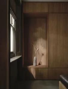 A dimly lit room with a wooden cabinet and a vase holding a flower, creating a calm and serene atmosphere