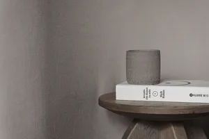 A wooden table with a book, vase, and cup on it, set in a cozy and comfortable space