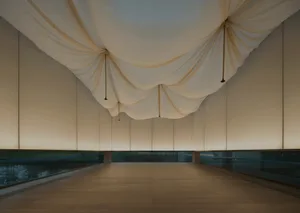 A large, empty lobby with white walls covered in fabric, a white floor, and a white ceiling, giving a clean and modern appearance