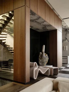 Warm and inviting living space with a wooden floor, spiral staircase, couch, chair, and vase, creating a comfortable atmosphere for relaxation and socializing
