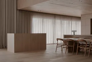 Warm and inviting kitchen with a wooden floor, wooden cabinets, and a dining table surrounded by chairs, under natural light