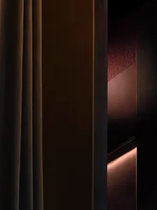 A dark hallway with a brown curtain covering the doorway, a wooden door, and a wooden frame