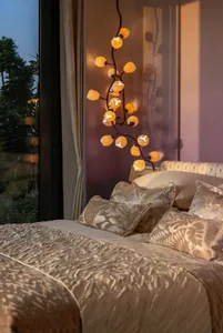 Cozy bedroom with a white comforter, a hanging lamp, and natural light from an open window
