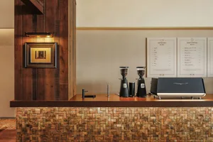 Cozy coffee shop with a wooden counter, black coffee machine, and two coffee makers, set against a neutral background