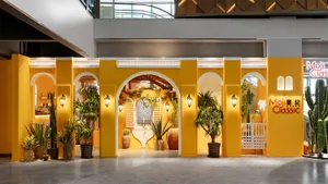 A brightly lit room with a yellow color scheme, featuring potted palm trees, vases, and bowls, creating a warm and inviting atmosphere