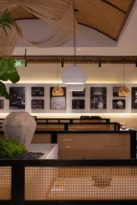 A modern restaurant interior with tables, chairs, artworks, and hanging lights creating a warm and inviting atmosphere