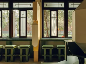 Cozy modern restaurant with green tables, chairs, and accents, natural light, and soft warm lighting