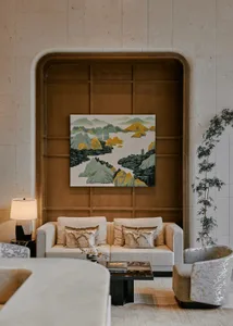 A well-lit living room with a couch, chair, and large painting on the wall, creating a comfortable and inviting atmosphere