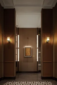 A dimly lit hallway with wooden walls, a doorway, and a yellow painting on the wall
