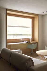 A well-lit living room with a couch, chair, and dining table, featuring wood and fabric materials and a cozy atmosphere
