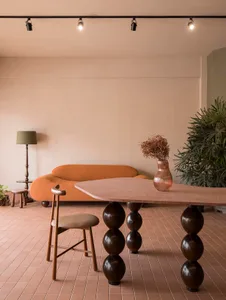 Cozy living room with a wooden floor, a couch, a chair, and a dining table, featuring a mix of natural and artificial lighting