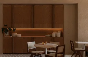 A cozy dining room with a wooden table and chairs, surrounded by cups and bowls, in a warm and intimate atmosphere