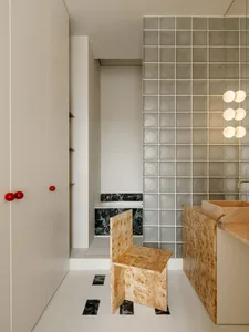 A modern kitchen with a tile wall, marble countertops, and a dimly lit atmosphere, featuring a sink, cabinet, and chair