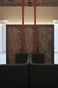 A waiting area with a wooden wall and a large bird painting, two chairs facing the painting, creating a warm and inviting space with a sense of elegance and sophistication